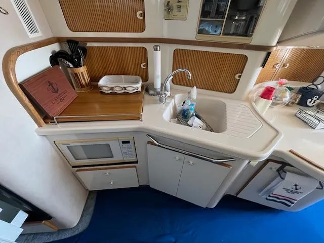 Papa's 7 II Yacht Photos Pics 1995 Sea Ray 440 Express Bridge kitchen with sink, microwave, and wooden accents.
