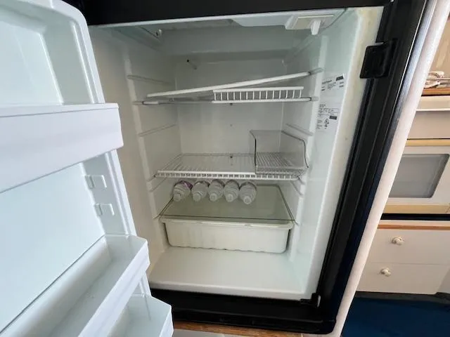 Papa's 7 II Yacht Photos Pics Open refrigerator inside a 1995 Sea Ray 440 Express Bridge yacht, containing water bottles.