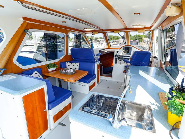  Yacht Photos Pics Interior of 2004 True North 38 boat with blue seating, wooden accents, and kitchen area.