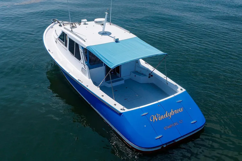  Yacht Photos Pics 2004 True North 38 boat with blue canopy on calm water.