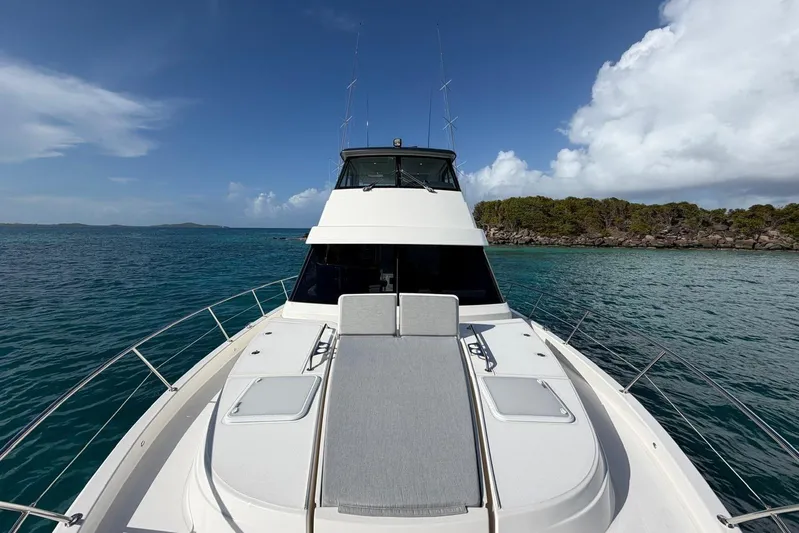  Yacht Photos Pics 2021 Riviera 50 Sports Motor Yacht on clear blue water, with lush island backdrop.