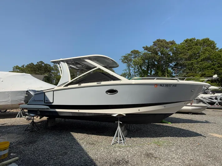  Yacht Photos Pics 2023 Chaparral 280 OSX boat on stands, outdoors, with trees in the background.