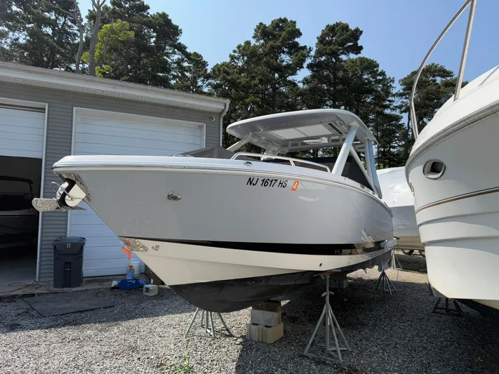  Yacht Photos Pics 2023 Chaparral 280 OSX boat on stands, parked outdoors near a garage.
