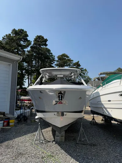  Yacht Photos Pics 2023 Chaparral 280 OSX boat on stands, surrounded by trees and other boats.