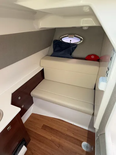 Yacht Photos Pics 2023 Chaparral 280 OSX cabin interior with seating, wood flooring, and porthole.
