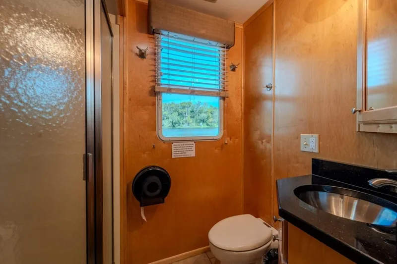 Southern Belle Yacht Photos Pics Bathroom interior of 2014 Sunstar Houseboats 55, featuring wood paneling and a window view.