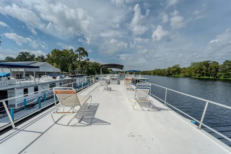 Southern Belle Yacht Photos Pics 2014 Sunstar Houseboats 55 on a serene river with deck chairs and clear skies.