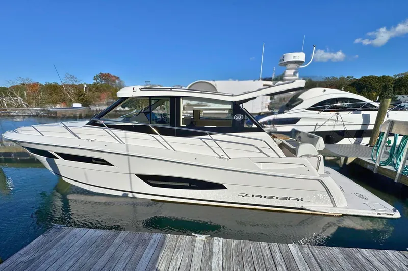  Yacht Photos Pics 2021 Regal 38 Grande Coupe yacht docked in a marina under clear blue skies.