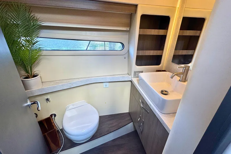 Yacht Photos Pics Luxurious bathroom in 2021 Regal 38 Grande Coupe yacht with modern fixtures and porthole view.
