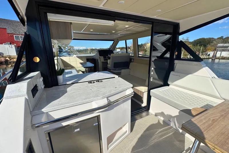  Yacht Photos Pics 2021 Regal 38 Grande Coupe interior with modern seating and kitchenette, dockside view.