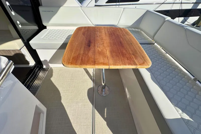  Yacht Photos Pics 2021 Regal 38 Grande Coupe interior with wooden table and white seating.