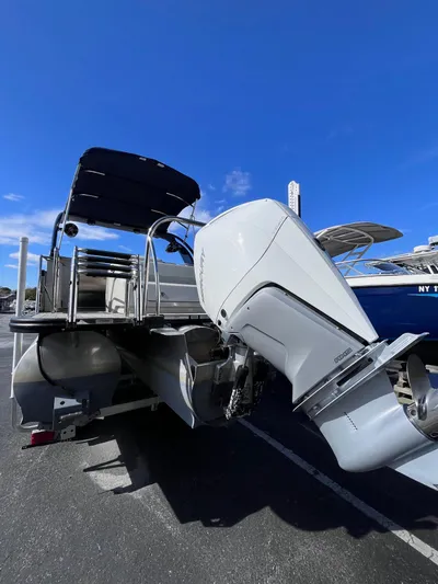  Yacht Photos Pics 2023 Avalon Excalibur Elite Windshield boat with powerful outboard motor, docked under clear blue sky.