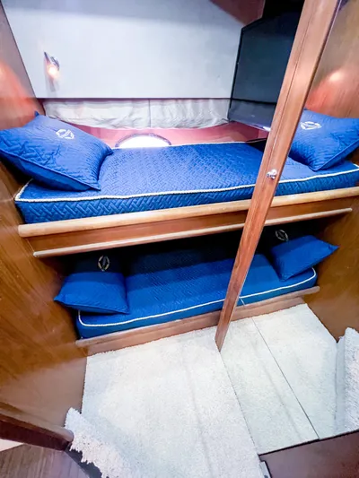  Yacht Photos Pics 2005 Sunseeker Predator 68 yacht cabin with blue bedding and wooden interior.