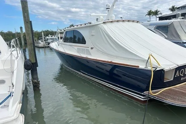 Aquarius Yacht Photos Pics 2024 Hinckley Talaria 43 MY yacht docked in marina, covered, with calm water and cloudy sky.