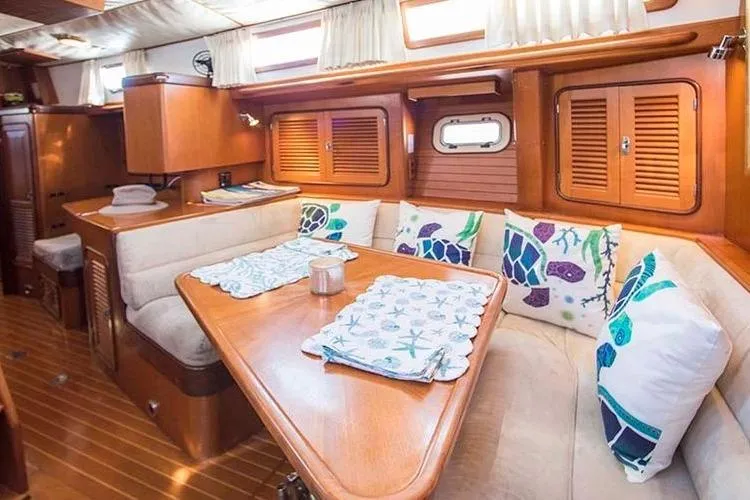 Wild Spirit Yacht Photos Pics Cozy yacht interior with wooden finish, cushioned seating, and nautical-themed pillows. Passport 456, 1999.