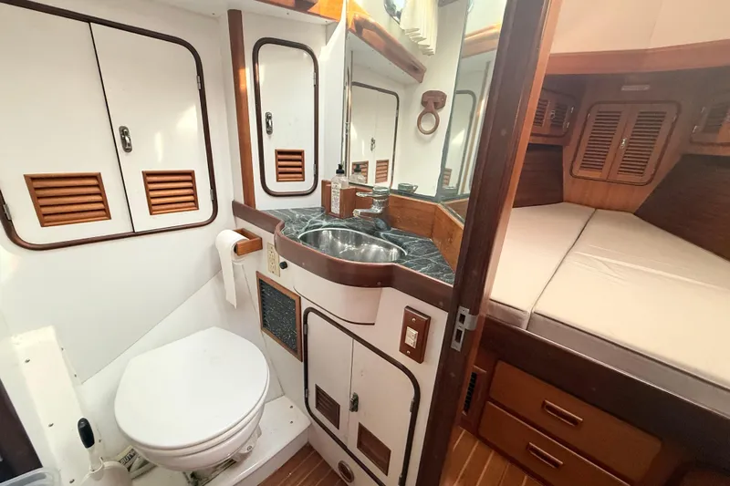 Wild Spirit Yacht Photos Pics Compact boat bathroom with sink, toilet, and adjacent sleeping area in a 1999 Passport 456.
