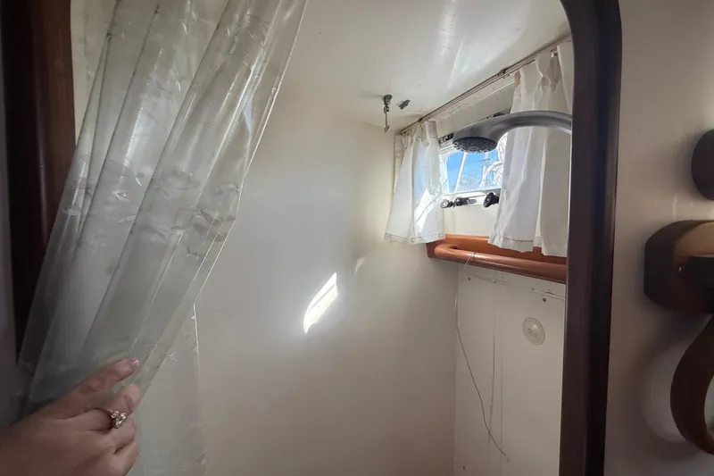 Wild Spirit Yacht Photos Pics Small boat shower area with curtain, window, and showerhead in a 1999 Passport 456.