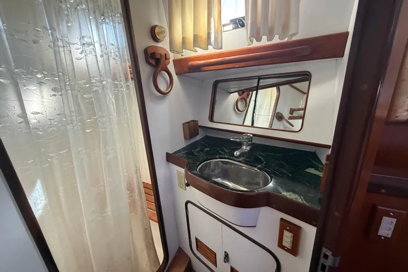 Wild Spirit Yacht Photos Pics Compact bathroom with green marble sink, mirror, and shower curtain in a 1999 Passport 456.