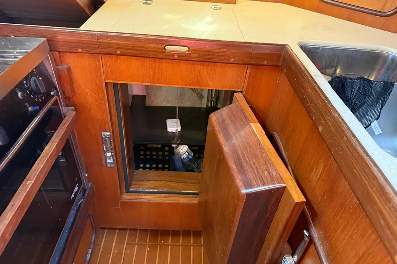 Wild Spirit Yacht Photos Pics Wooden kitchen cabinet with open door, revealing storage space, in a 1999 Passport 456 model.
