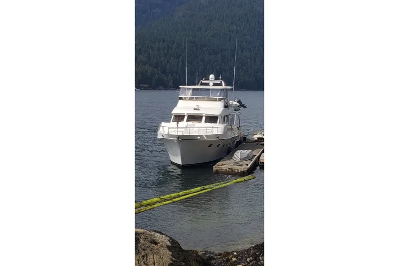 Katula Yacht Photos Pics 2003 Mikelson Long Range Cockpit MY yacht docked in a serene, forested harbor.
