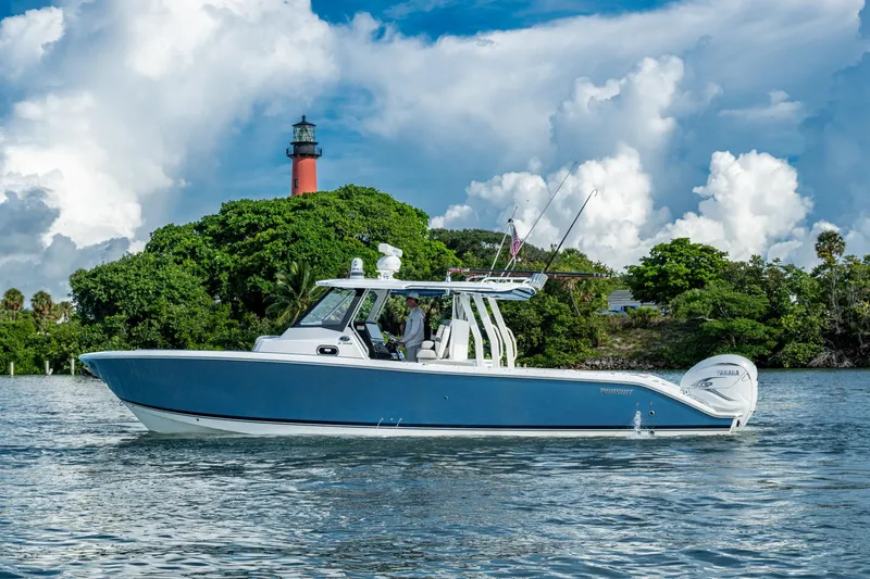 Island Girl II Yacht Photos Pics 2023 Pursuit S 358 Sport boat cruising near a lighthouse with lush greenery.