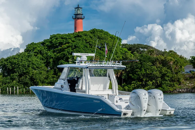 Island Girl II Yacht Photos Pics 2023 Pursuit S 358 Sport boat cruising near a lighthouse with lush greenery.