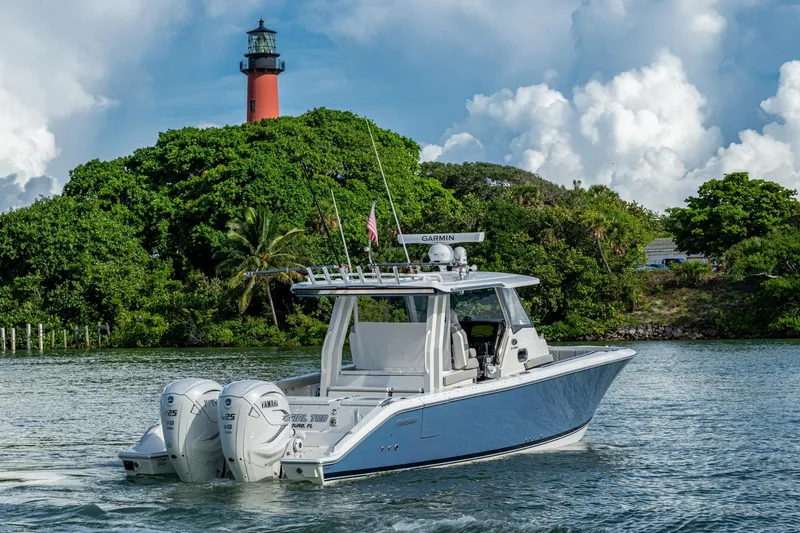 Island Girl II Yacht Photos Pics 2023 Pursuit S 358 Sport boat cruising near a lighthouse and lush greenery.