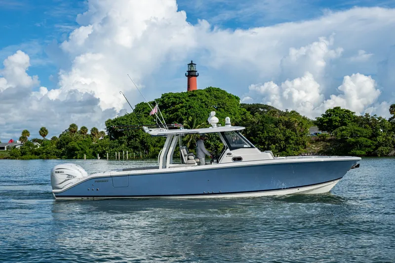 Island Girl II Yacht Photos Pics 2023 Pursuit S 358 Sport boat cruising near lush island and lighthouse.