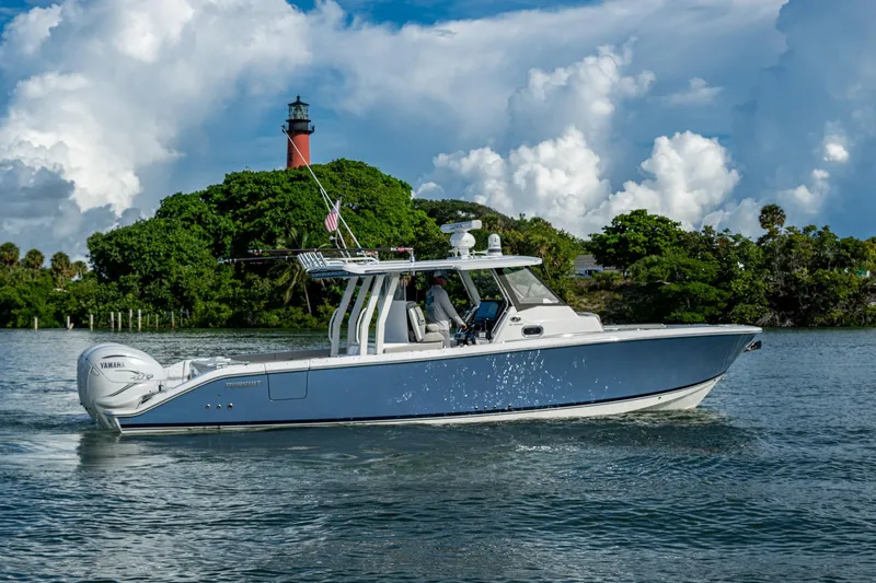 Island Girl II Yacht Photos Pics 2023 Pursuit S 358 Sport boat cruising near a lighthouse with lush greenery.