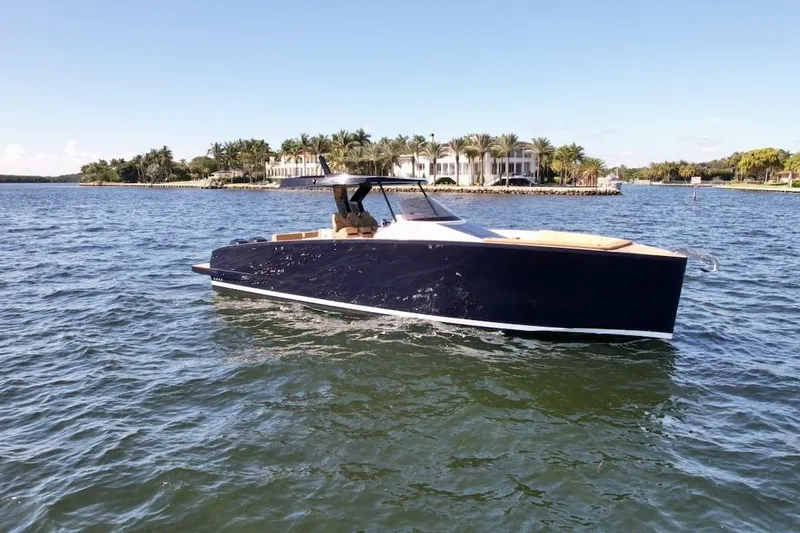  Yacht Photos Pics 2023 Tesoro T38 luxury yacht cruising on a sunny day near a waterfront mansion.