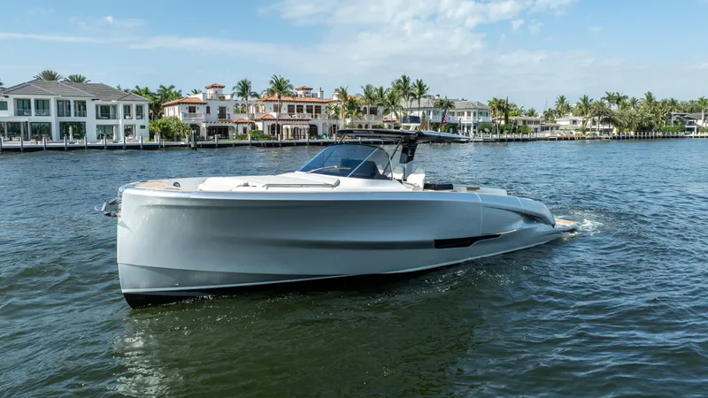  Yacht Photos Pics 2025 Solaris Power 44 Open yacht cruising near waterfront homes under a clear sky.