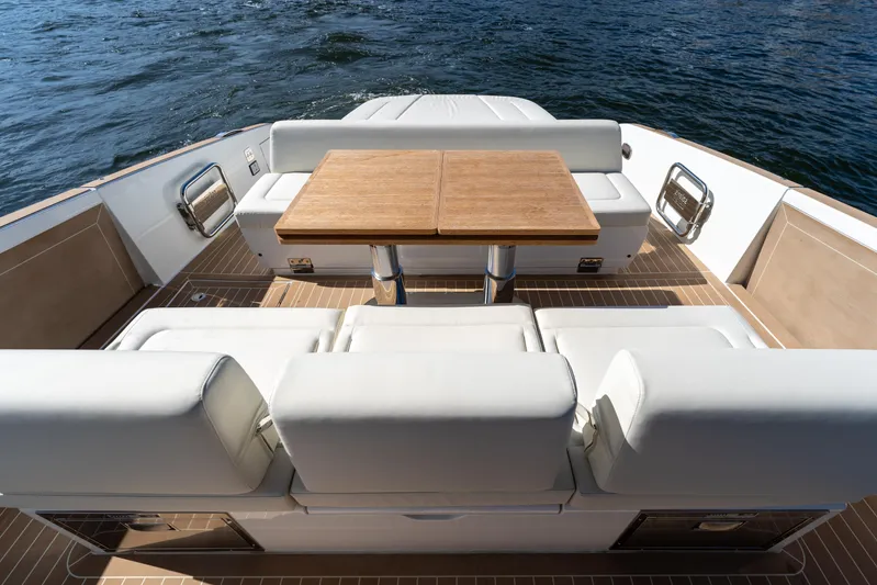  Yacht Photos Pics Luxurious seating area on 2025 Solaris Power 44 Open yacht with wooden table, overlooking water.