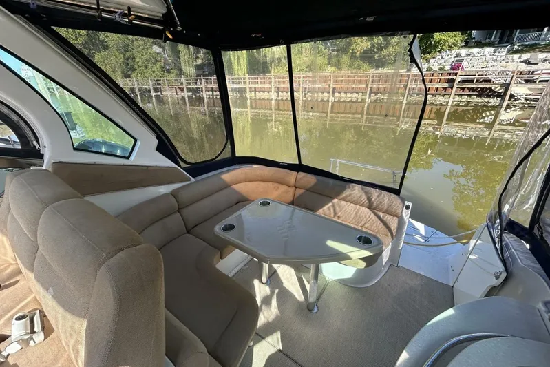  Yacht Photos Pics 2011 Four Winns V335 boat interior with beige seating and table, overlooking a calm waterfront.