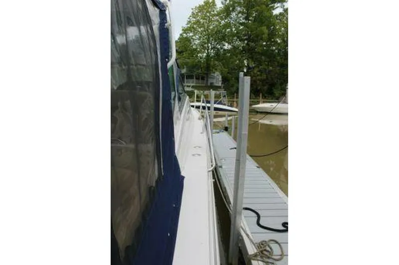  Yacht Photos Pics 2011 Four Winns V335 yacht docked beside a pier, featuring blue canvas cover.