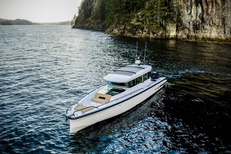  Yacht Photos Pics 2025 Axopar 37XC CROSS CABIN BRABUS Trim cruising near rocky shoreline.