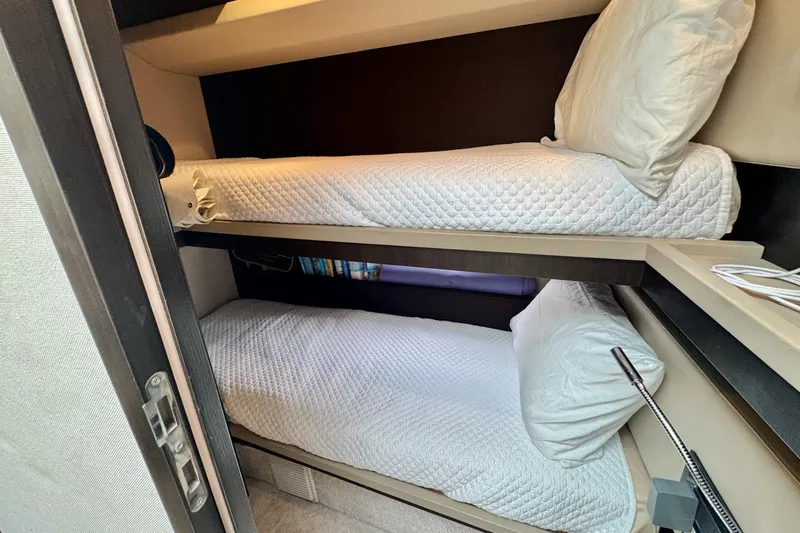 Kiki Yacht Photos Pics Bunk beds in 2016 Azimut 66 yacht cabin, featuring cozy white bedding.