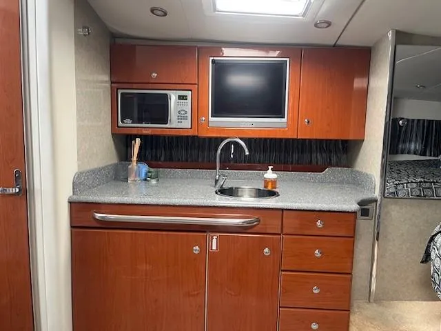  Yacht Photos Pics 2005 Formula 34PC yacht kitchen with wood cabinets, sink, microwave, and TV.