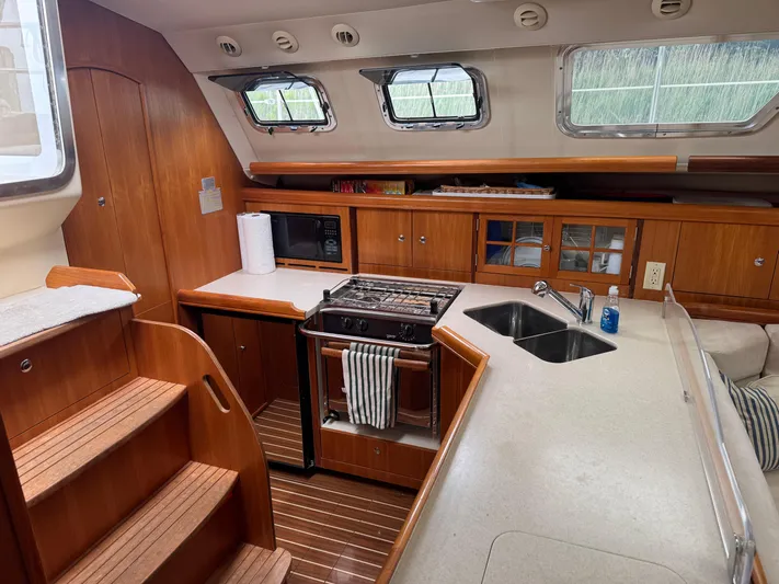 Strider Yacht Photos Pics 2006 Hunter 41 Deck Salon interior with wooden cabinetry, kitchen, and stairs.