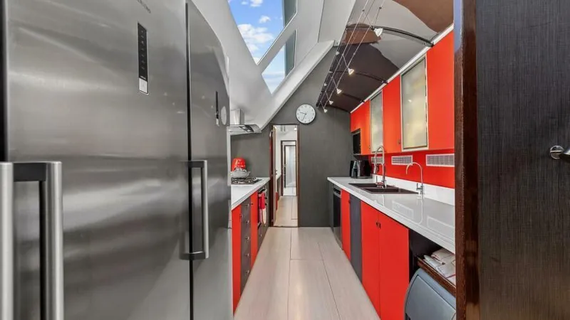 Skye Yacht Photos Pics Modern yacht kitchen with red cabinets, stainless steel appliances, and sleek design, 2023 Mystique Yachts.