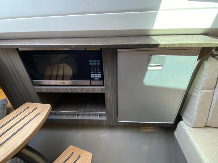 Aquaholic Yacht Photos Pics 2023 Sea Ray SLX 400 interior with microwave and compact fridge in modern kitchenette.