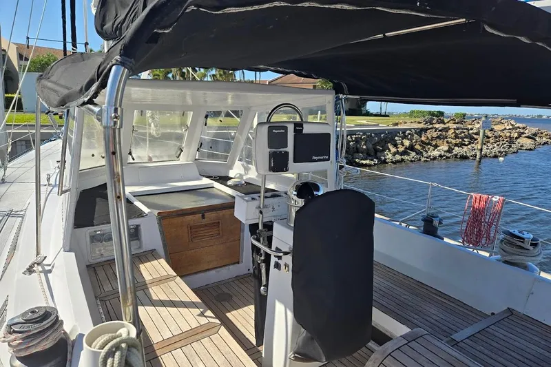 Cookie Monster Too Yacht Photos Pics 1982 Tayana Center Cockpit Cutter Ketch with covered helm, docked by rocky shoreline.