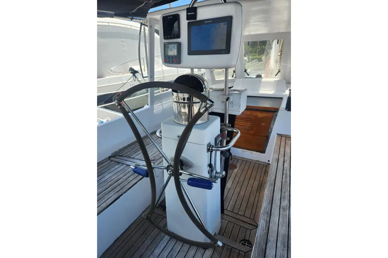 Cookie Monster Too Yacht Photos Pics 1982 Tayana Center Cockpit Cutter Ketch helm with navigation equipment and wooden deck.