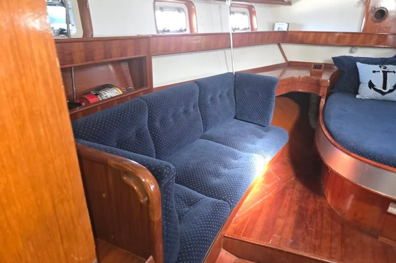 Cookie Monster Too Yacht Photos Pics Interior of 1982 Tayana Center Cockpit Cutter Ketch with blue seating and wooden accents.