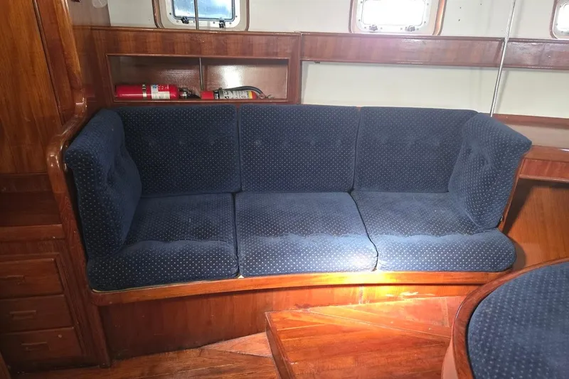 Cookie Monster Too Yacht Photos Pics 1982 Tayana Center Cockpit Cutter Ketch interior with blue cushioned seating and wooden finish.