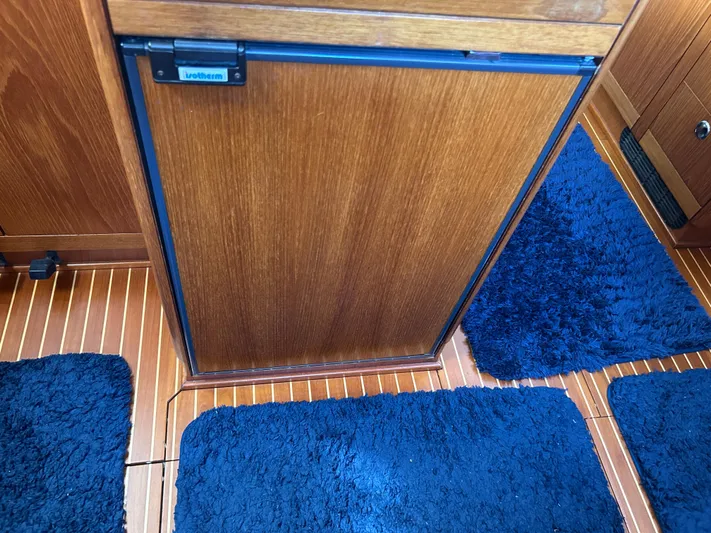 Kells Yacht Photos Pics Wooden interior of 1996 Nautor Swan 44 Mk II yacht with blue rugs and fridge.