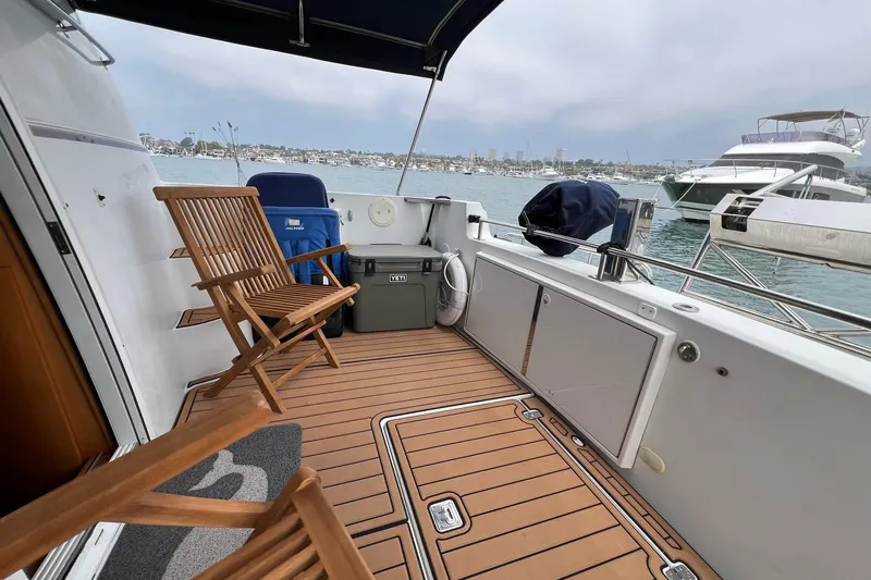  Yacht Photos Pics 2003 Carver 444 Cockpit Motor Yacht with wooden deck chairs and scenic harbor view.