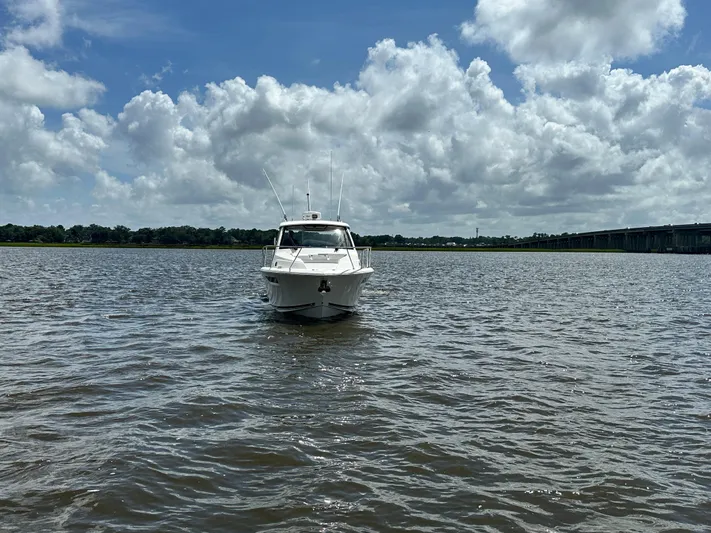  Yacht Photos Pics 2023 Pursuit OS 325 Offshore boat on calm water under a cloudy sky.