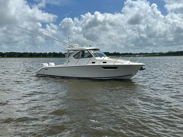  Yacht Photos Pics 2023 Pursuit OS 325 Offshore boat on calm water under a cloudy sky.