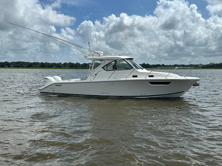  Yacht Photos Pics 2023 Pursuit OS 325 Offshore boat on calm water under cloudy sky.
