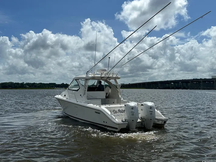  Yacht Photos Pics 2023 Pursuit OS 325 Offshore boat cruising on a sunny day with fishing rods.
